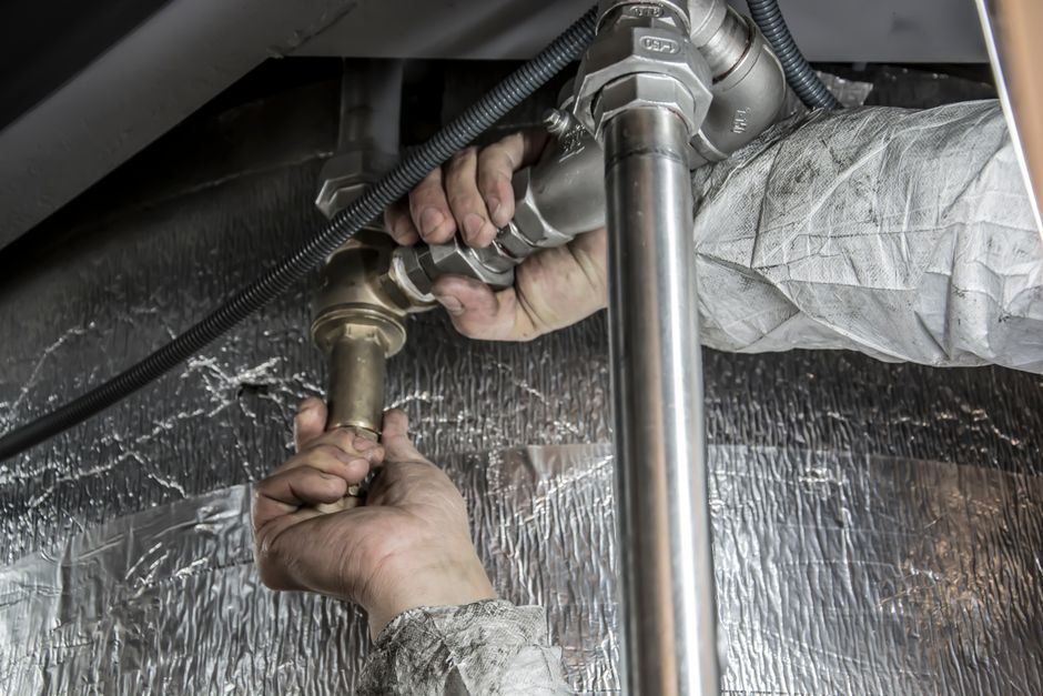 Close-up of a plumber's hands fitting brass pipe valves